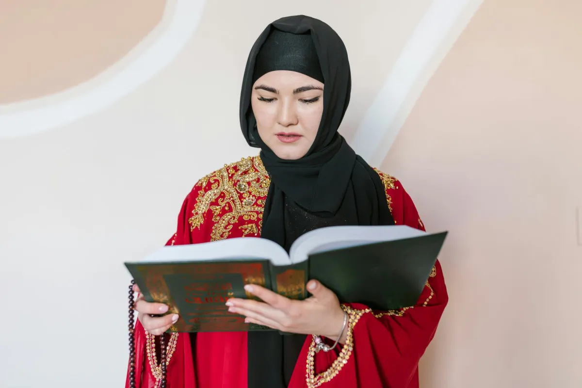 سيدة تمسك بمصحف شريف تتلو آيات من القرآن الكريم