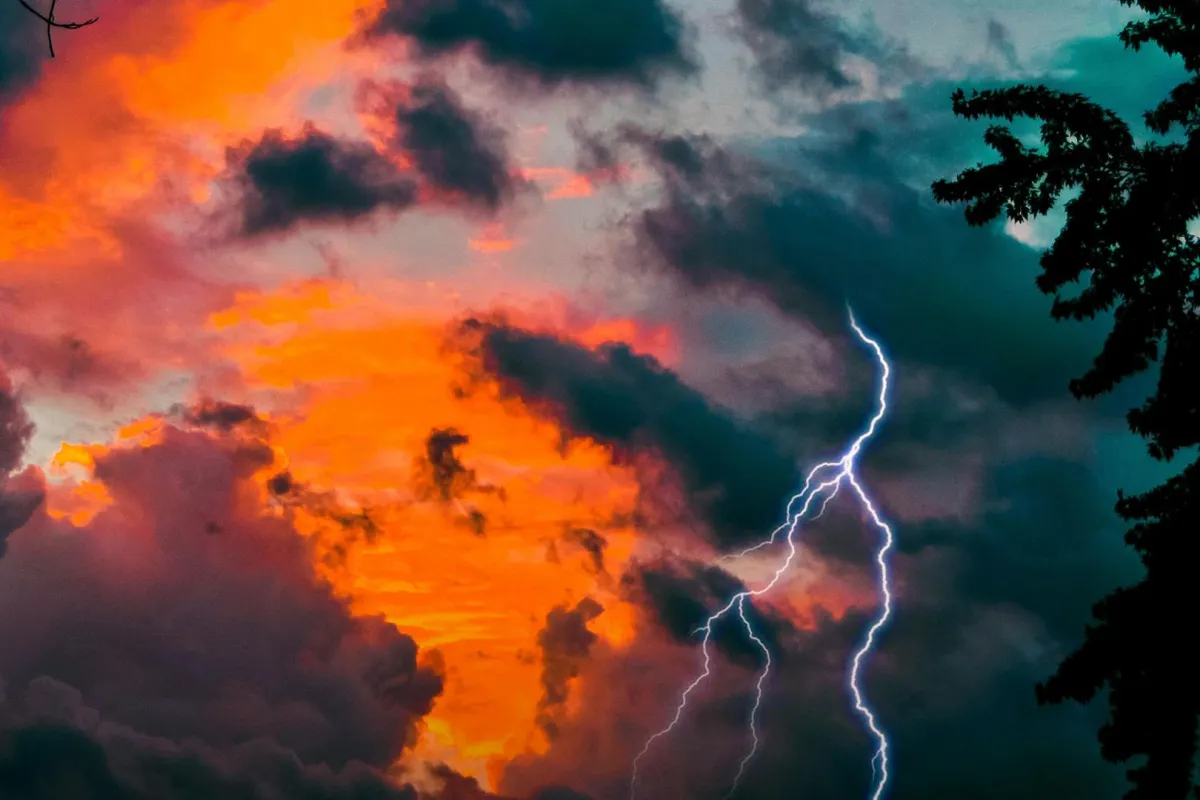 برق في سماء مشمسة وسحب متشحة بلون برتقالي 