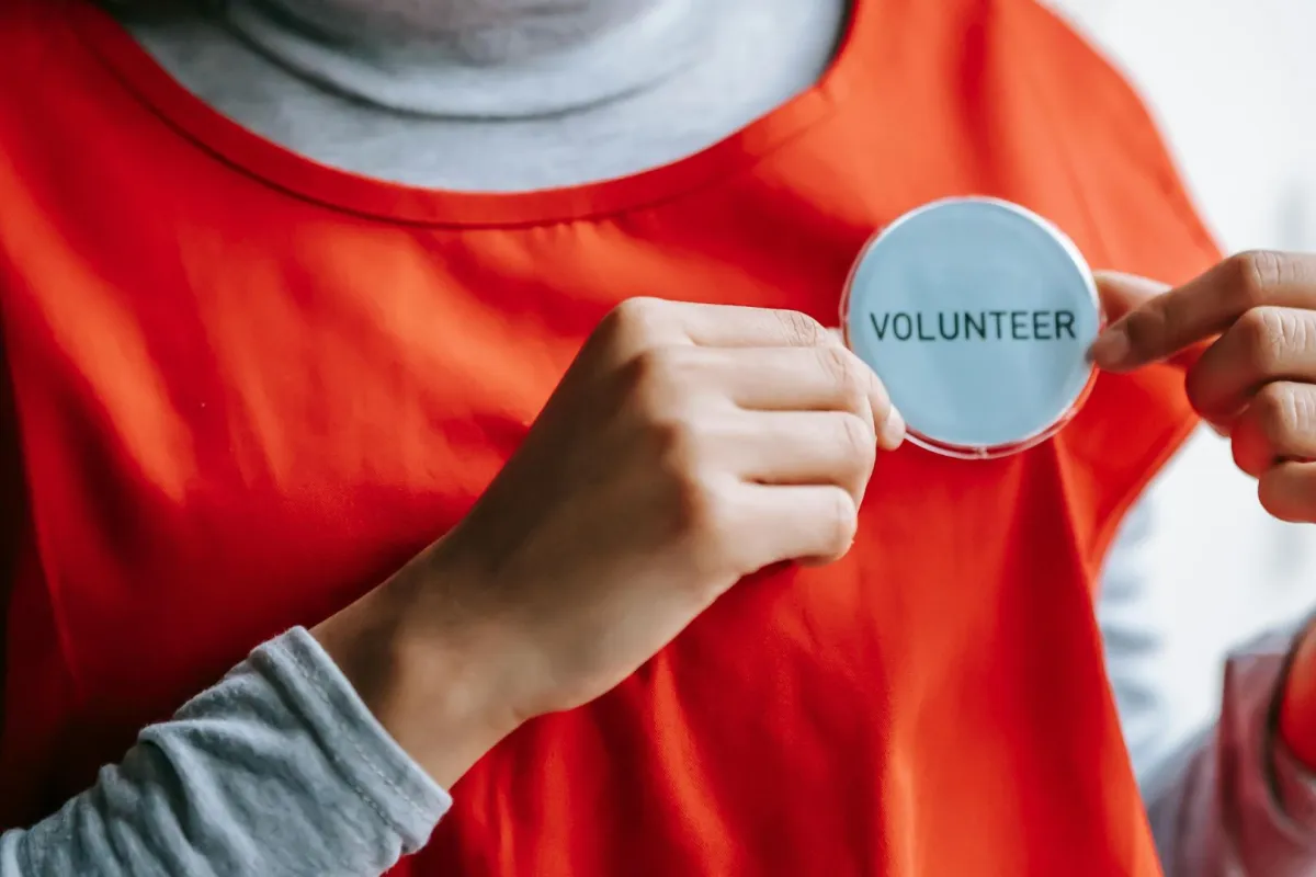 شابة تستعرض شارة التطوع من على ملابسها بفخر