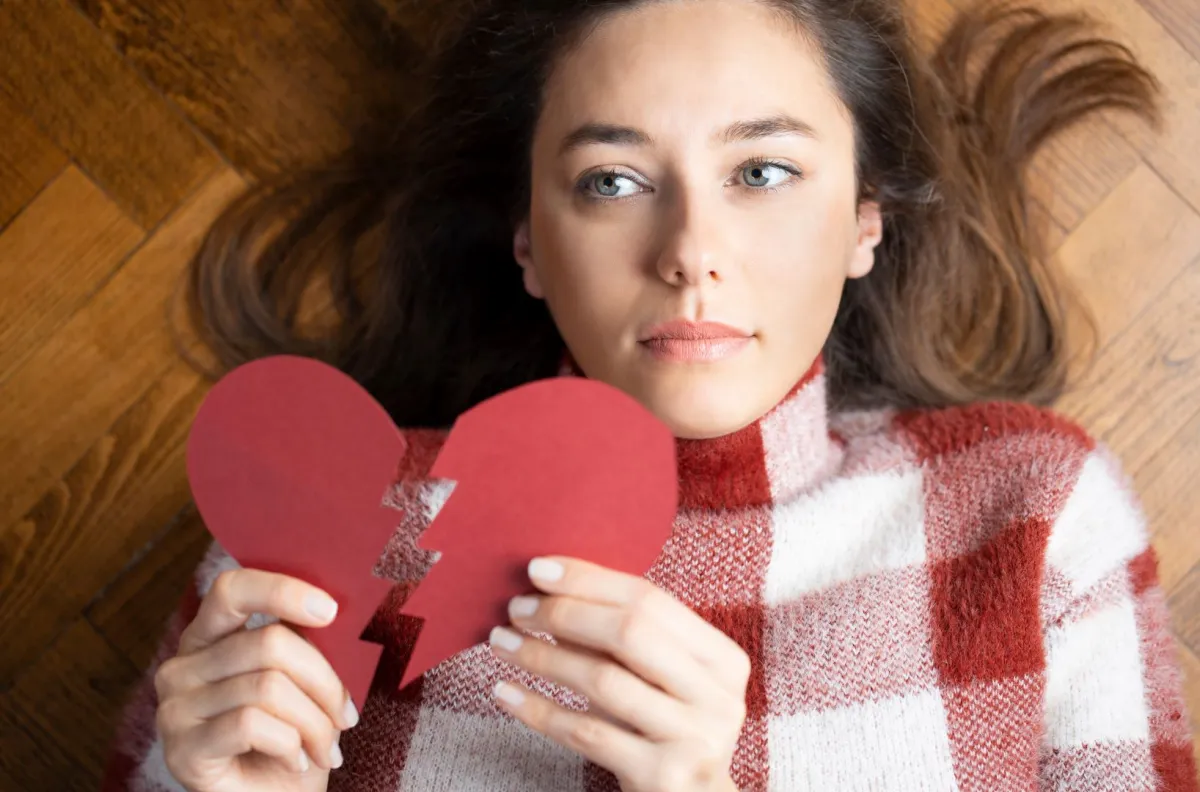 امرأة شابة تحمل شكل قلب مكسور