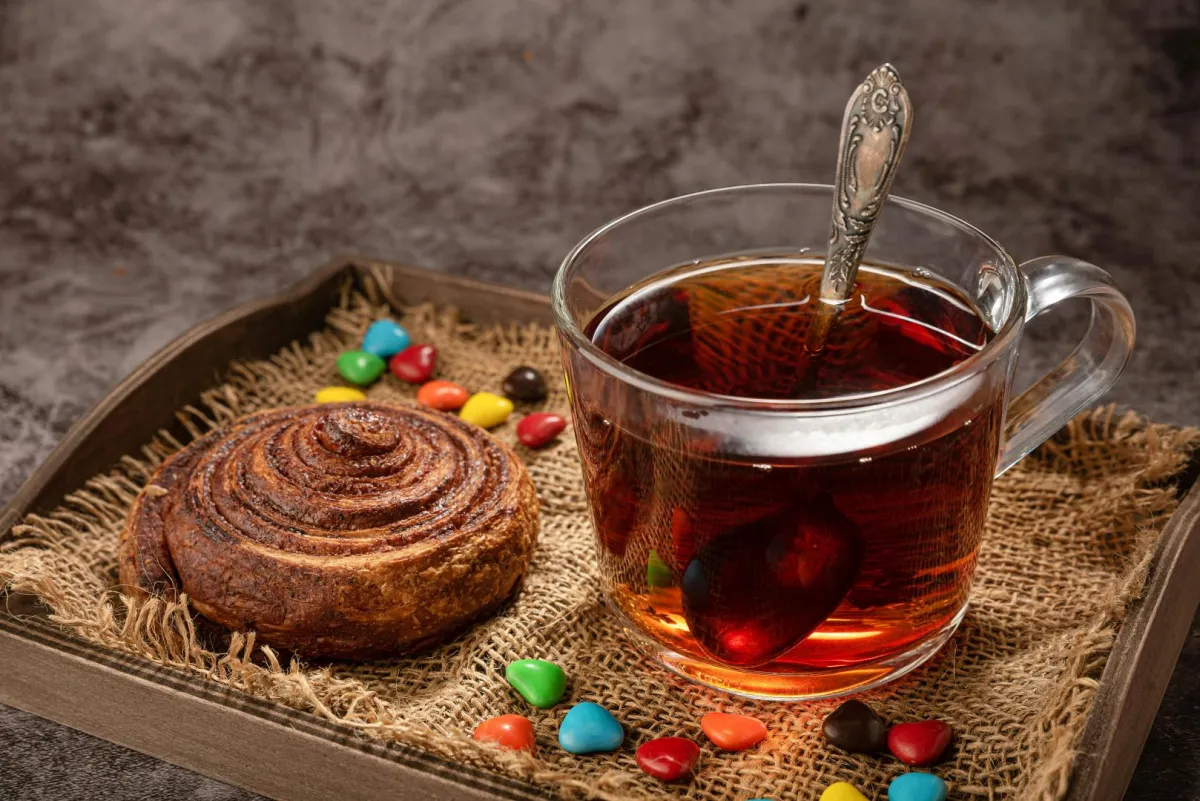 فنجان من الشاي اللذيذ وبجانبه مخبوزات وحلوى ملونة