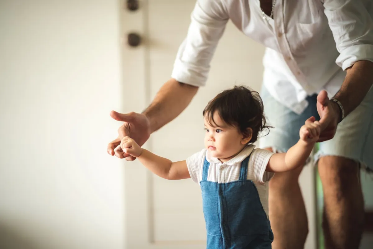 صورة أب يساعد طفله على المشي