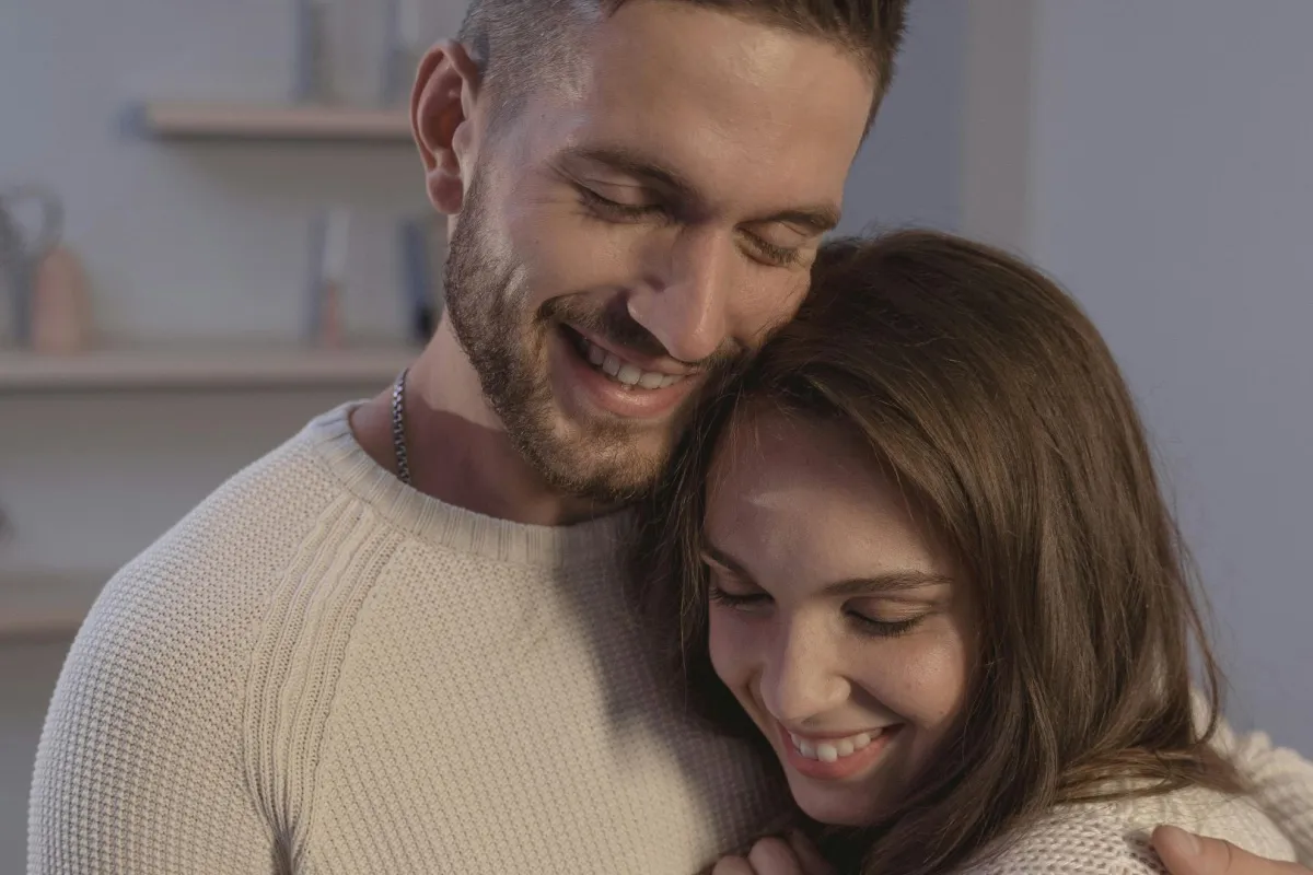 زوج محب يحتضن كتف زوجته بدفء وهما يبتسمان