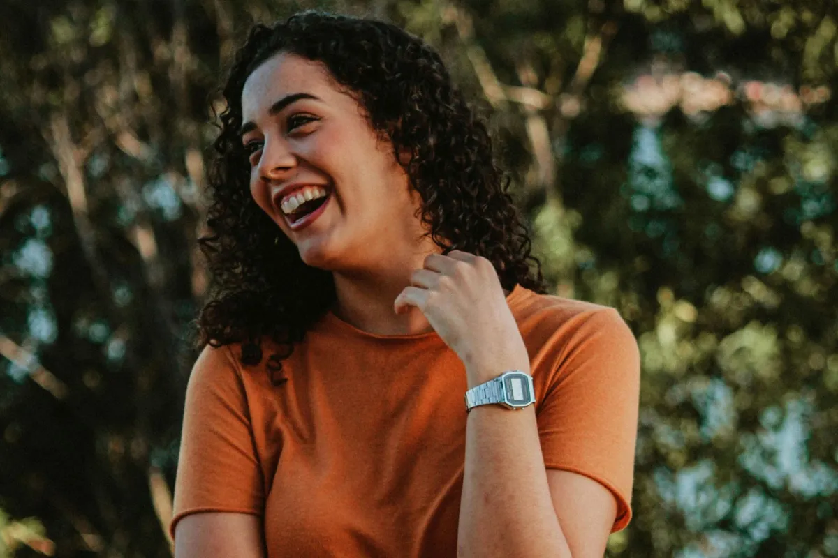 فتاة تضع يدها على رقبتها وهي تضحك