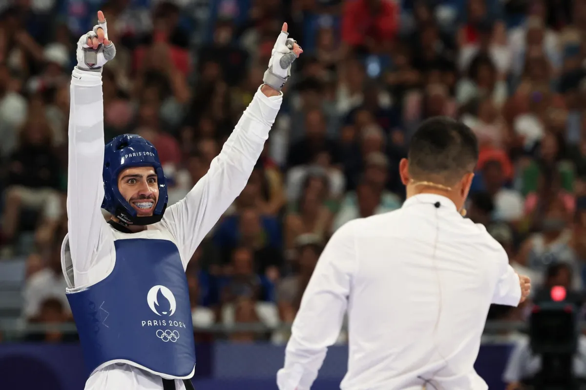 الأردني زيد كريم- Jordan's Zaid Kareem (L) celebrates after winning in the taekwondo men's -68kg quarter-final bout of the Paris 2024 Olympic Games at the Grand Palais in Paris on August 8, 2024. (Photo by David GRAY / AFP) 