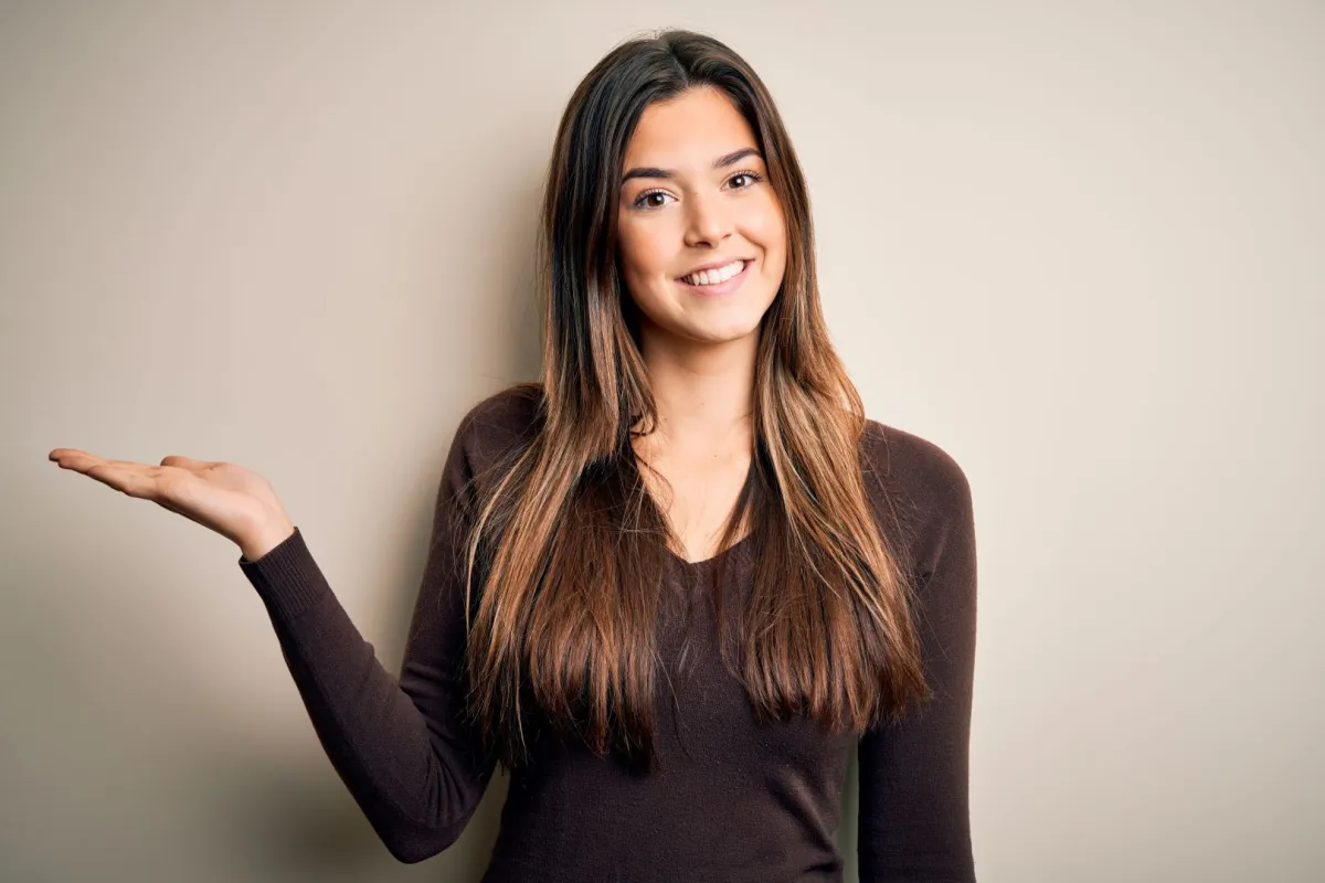 فتاة جميلة تبتسم بمرح وتشير براحة يدها وتنظر