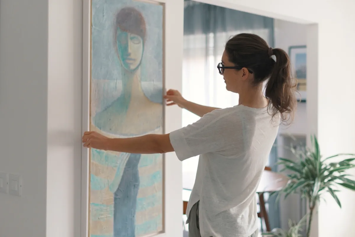 سيدة تزين منزلها بلوحة فنية- الصورة تعبيرية