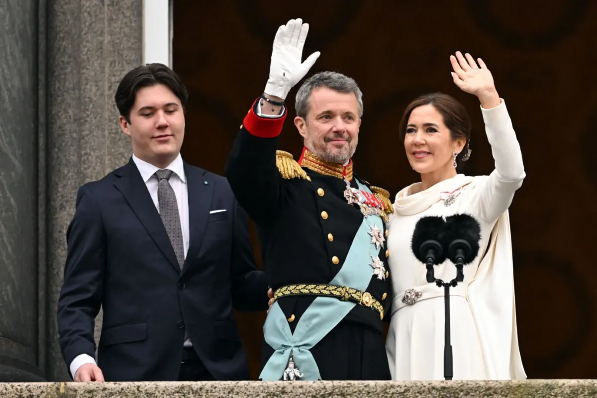 الملك فريدريك العاشر والملكة ماري بجوار ابنهما ولي العهد كريستيان يقفان على شرفة قصر كريستيانسبورغ في كوبنهاغن، الدنمارك (King Frederik X and Queen Mary next to their son, the new Crown Prince Christian stand on the balcony of Christiansborg Palace in Copenhagen, Denmark). مصدر الصورة: Jonathan NACKSTRAND / AFP