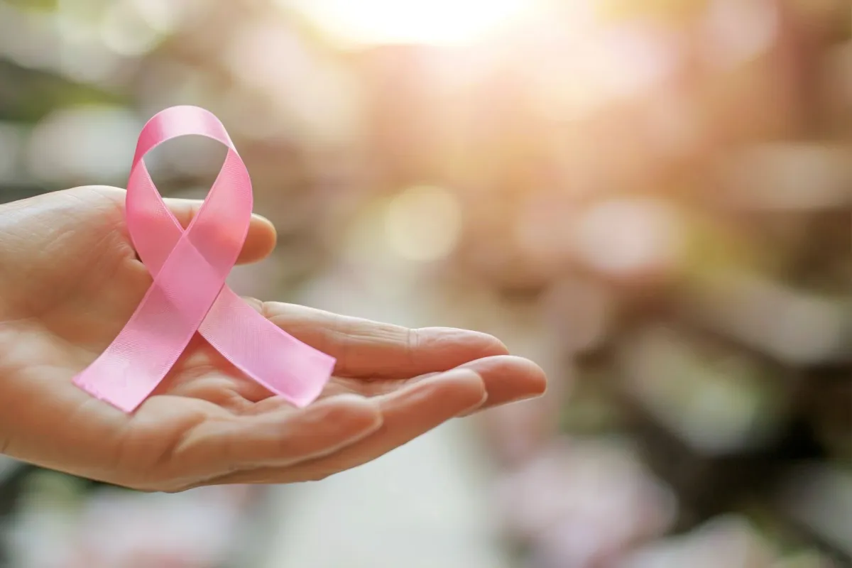 سيدة تمسك بيدها شارة سرطان الثدي الوردية