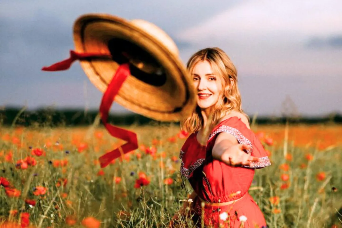 فتاة تلقي بقبعتها ببهجة ومرح وسط حقول الزهور