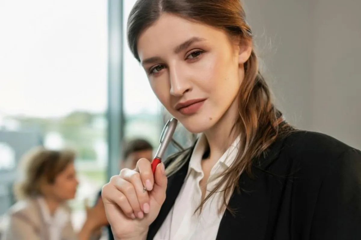  شابة تبدو ذات استقلال شخصي تنظر بثقة وتُشير بقلمها باعتداد