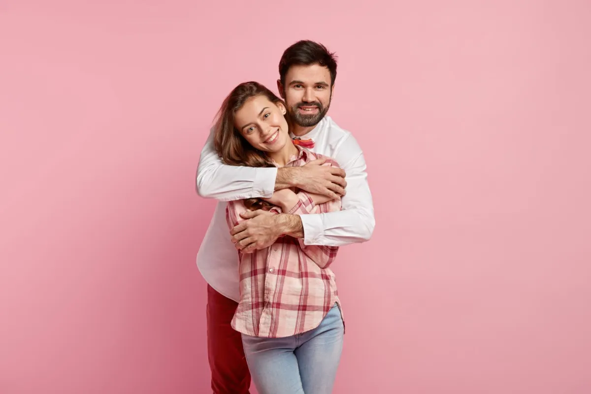 زوج يحتضن زوجته بحنان وهي تبتسم له بسعادة 
