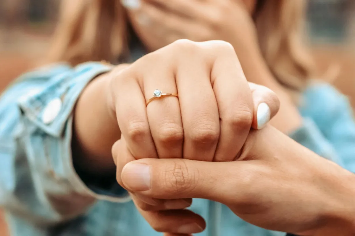 خطيب يمسك يد خطيبته وهي تستعرض خاتم خطوبتهما بسعادة