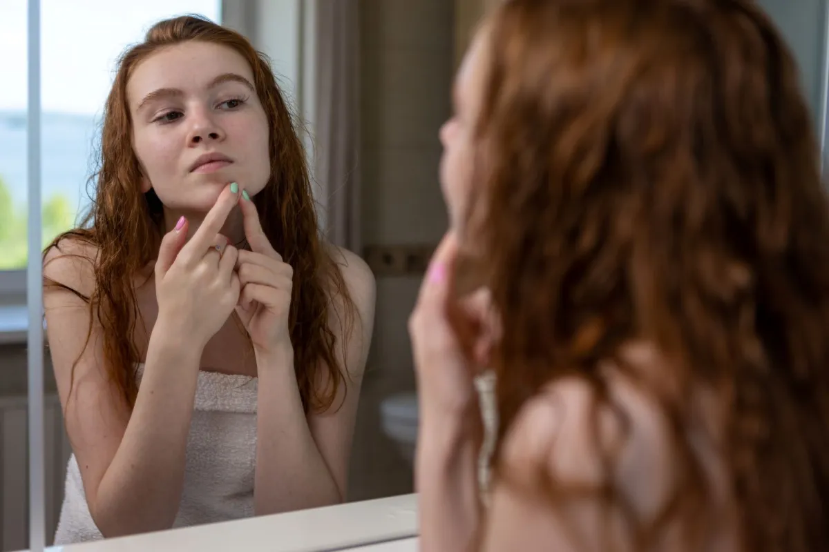 صورة مراهقة تتفقد بشرتها