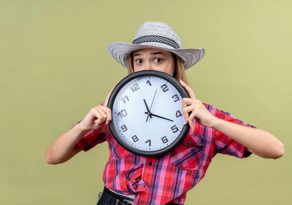   شابة تمسك بيدها ساعة كبيرة وتبدو خائفة من ضياع وقتها   