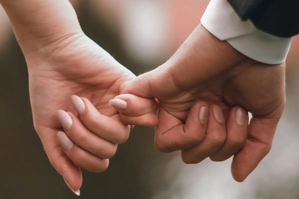 زوجان يمسك كل منهما بإصبع الآخر الصغير دليل على قوة علاقتهما