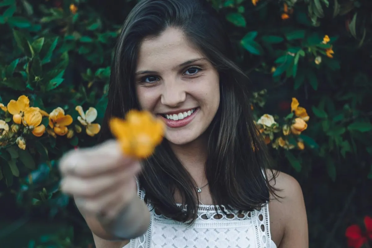 فتاة متفائلة تحمل بزهرة مشرقة 