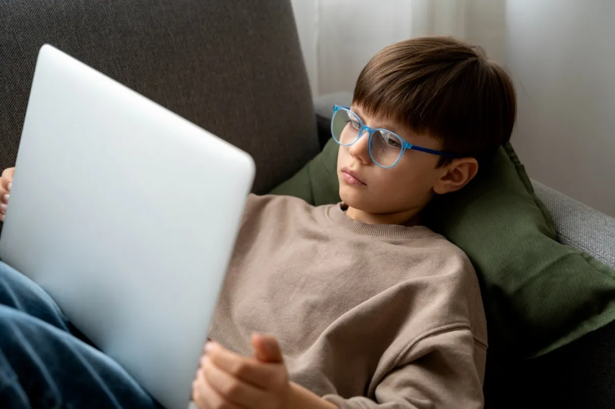 صورة لطفل مندمج مع جهازه الاليكتروني