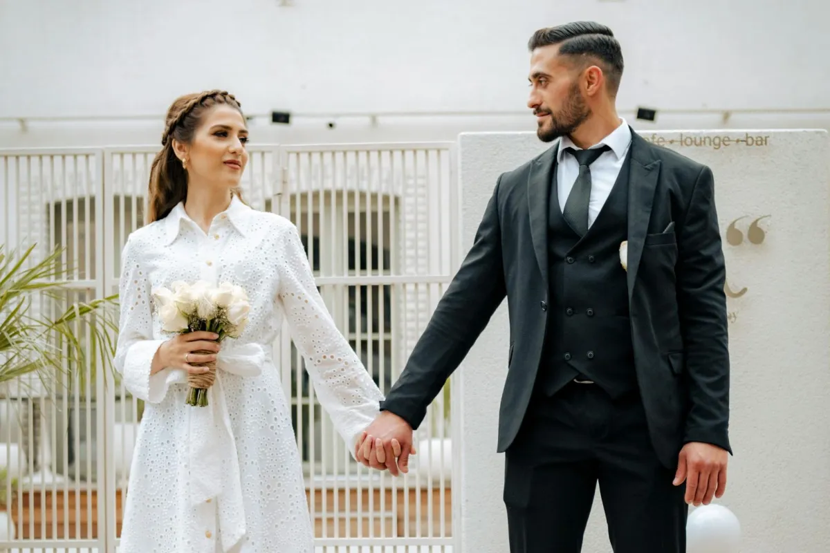 خطيبان يمسك كل خطيب بيد الآخر بسعادة والخطيبة تمسك بيدها باقة من الزهور