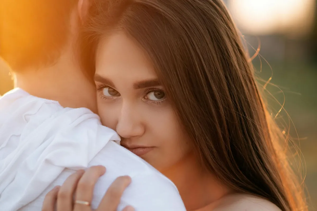 زوج يحتضن زوجته وهي تنظر بنظرة مليئة بالتوقعات المستقبلية