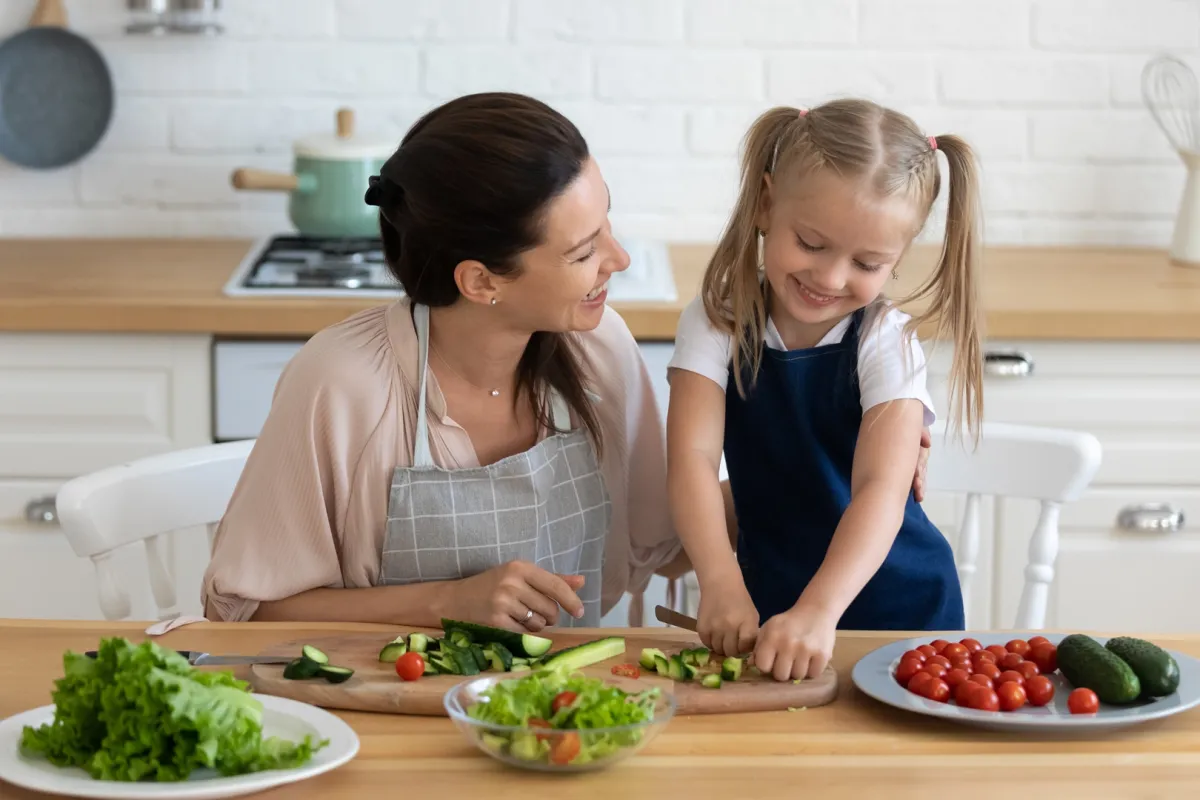 ام تحاول تعليم ابنتها كيف تساعدها في المطبخ