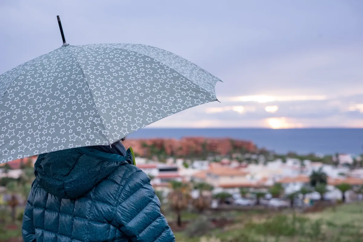 مسافرة تستمتع برحلتها السياحية تحت المطر