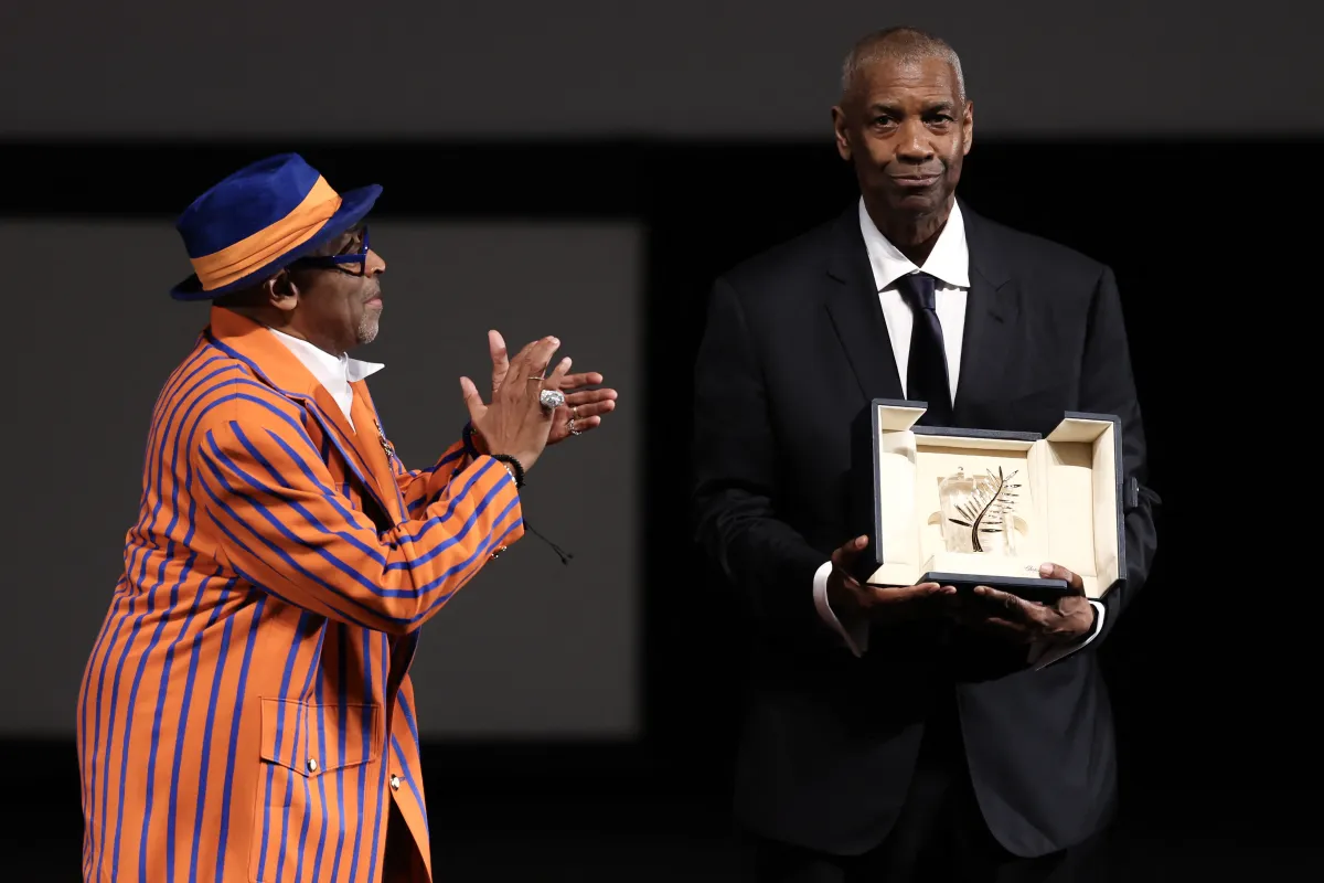 دينزل واشنطن يتسلم السعفة الذهبية الفخرية من المخرج سبايك لي في الدورة 78 من مهرجان كان السينمائي (Denzel Washington receives the Honorary Palme d'Or from director Spike Lee at the 78th edition of the Cannes Film Festival). مصدر الصورة:Sameer AL-DOUMY / POOL / AFP