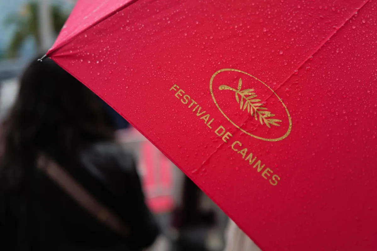 أحد المارة يحمل مظلة عليها شعار السعفة الذهبية في كان، جنوب فرنسا (A pedestrian holds an umbrella with the logo of the Palme d'Or in Cannes, southern France). مصدر الصورة: Valery HACHE / AFP