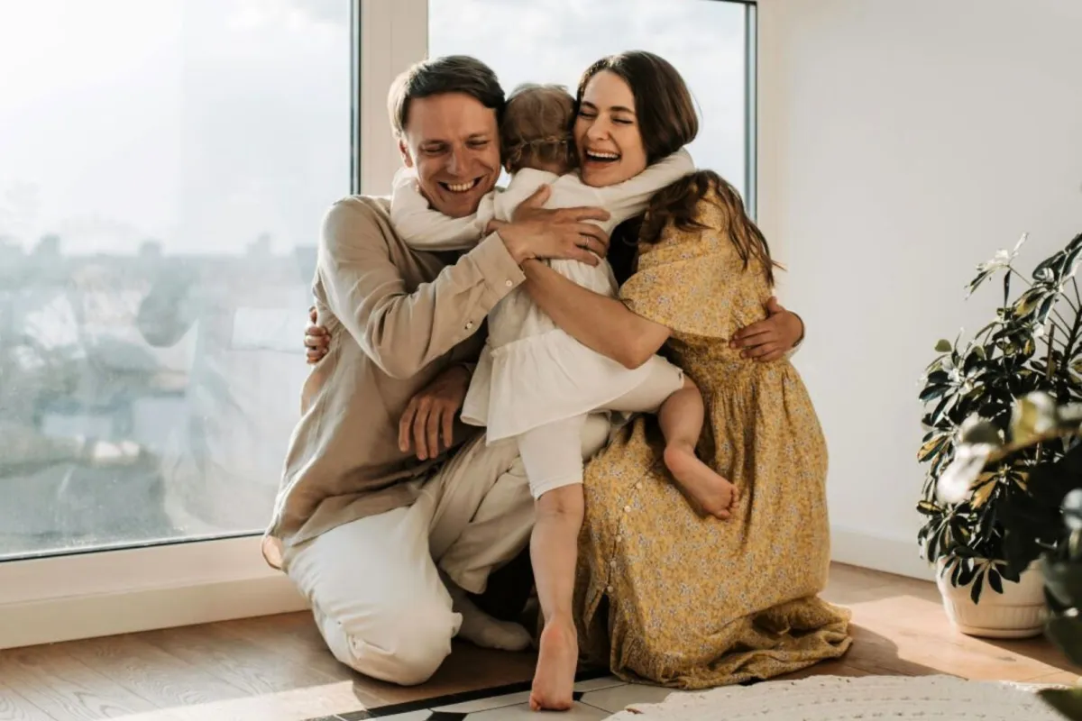 طفل يحتضن والديه وهما يحضنونه بمحبة 