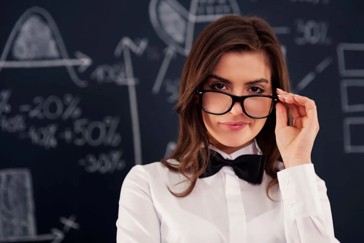 امرأة تبدو واثقة من نفسها وتمسك نظارتها بطرف إصبعها   