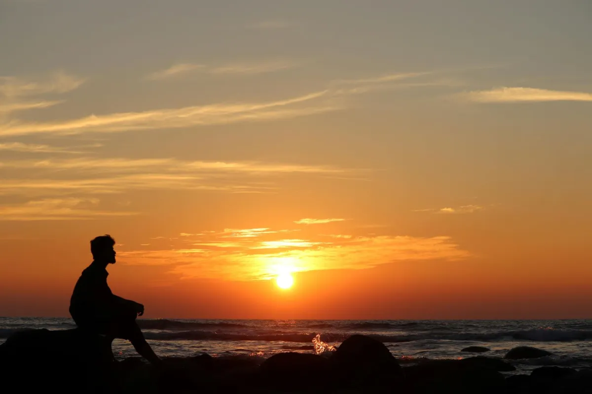 شاب يجلس على البحر يتأمل الغروب