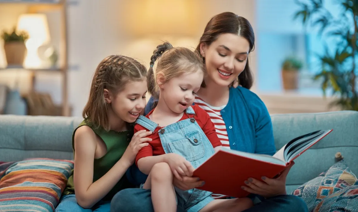 صورة لأم تقرأ قصة لطفلتيها