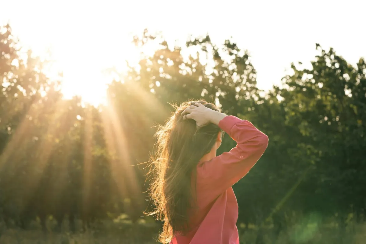 فتاة تنظر إلى شروق الشمس والمستقبل بتفاؤل