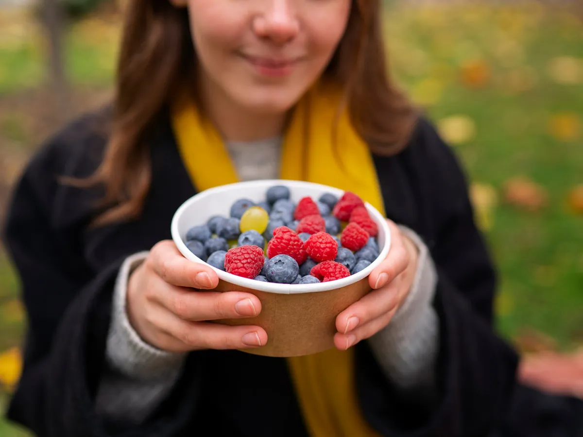 فتاة تحمل طبقاً مليئاً بالفواكه الفواكة  Image By Freepik