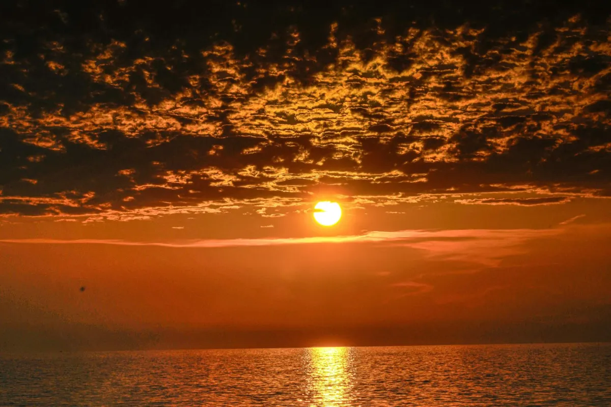 الشمس تغرب من بين السحاب لتختفي بين أمواج المحيط البعيدة