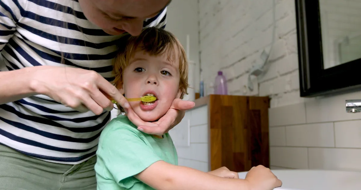 صورة أم تساعد طفلها على تنظيف أسنانه