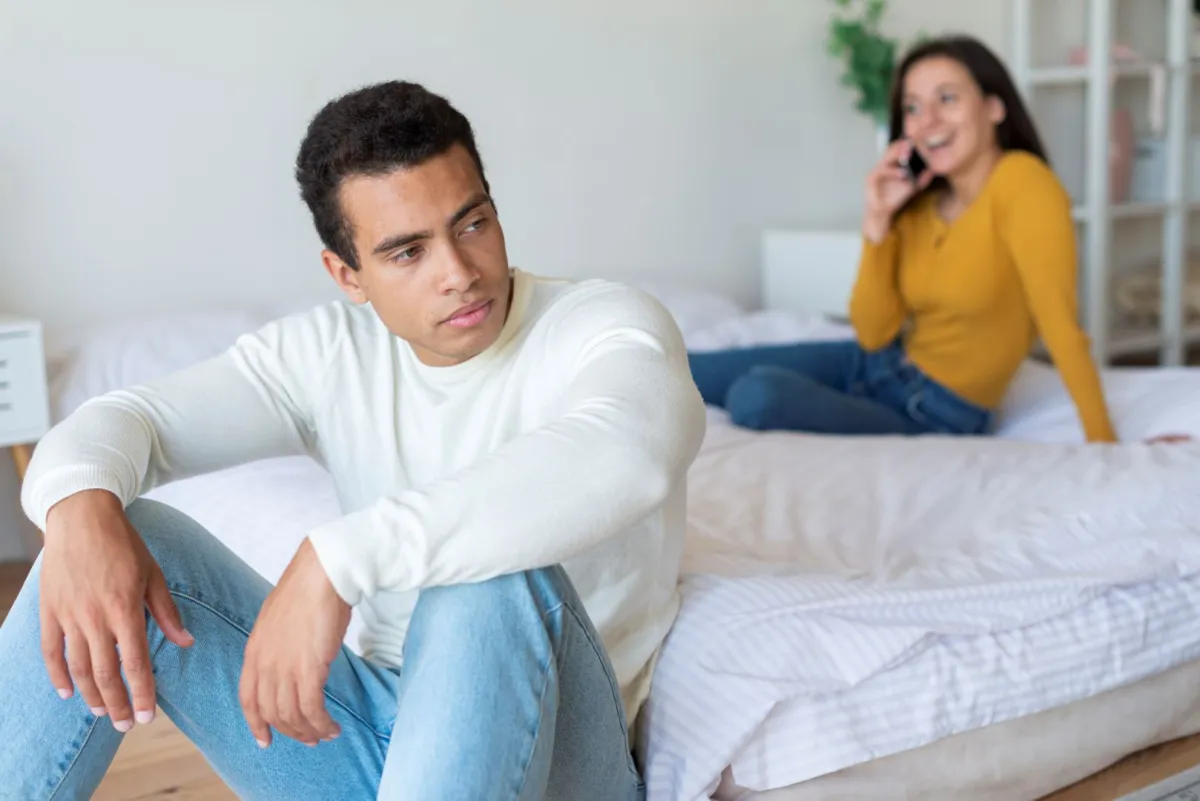 زوج يبدو غيورا غاضبًٍا من زوجته ومتضايق وهي تتحدث بالهاتف 