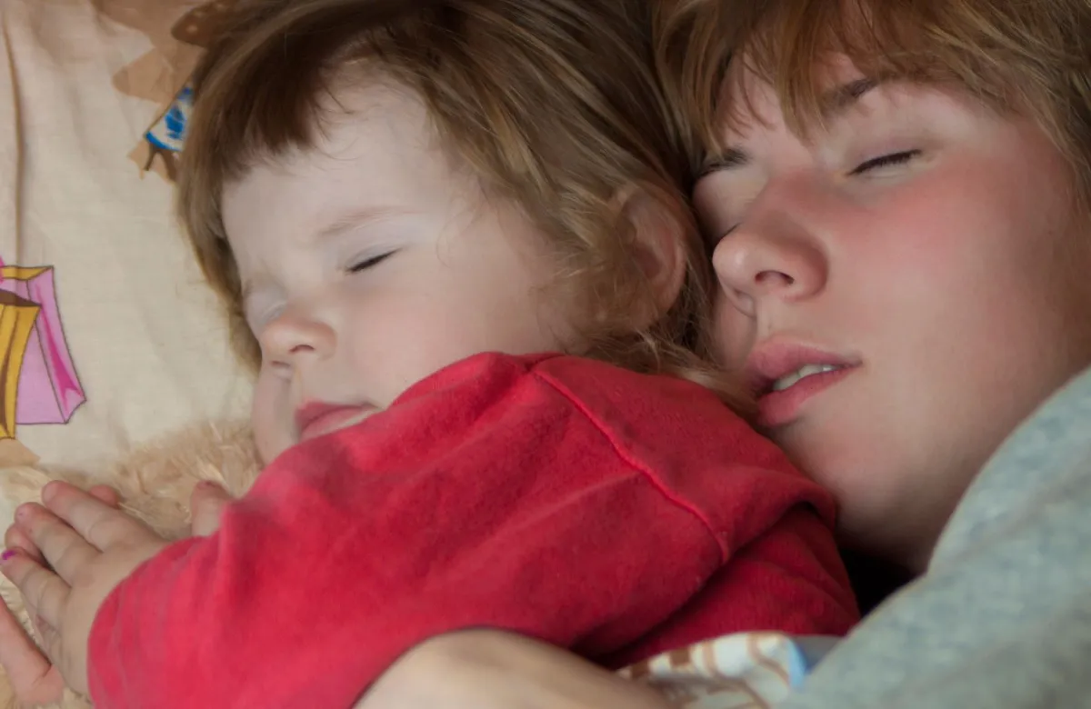 صورة طفل ينام بجانب أمه