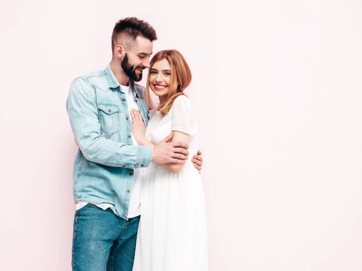 زوج يحتضن زوجته بمحبة وهي مشرقة وتبتسم بسعادة