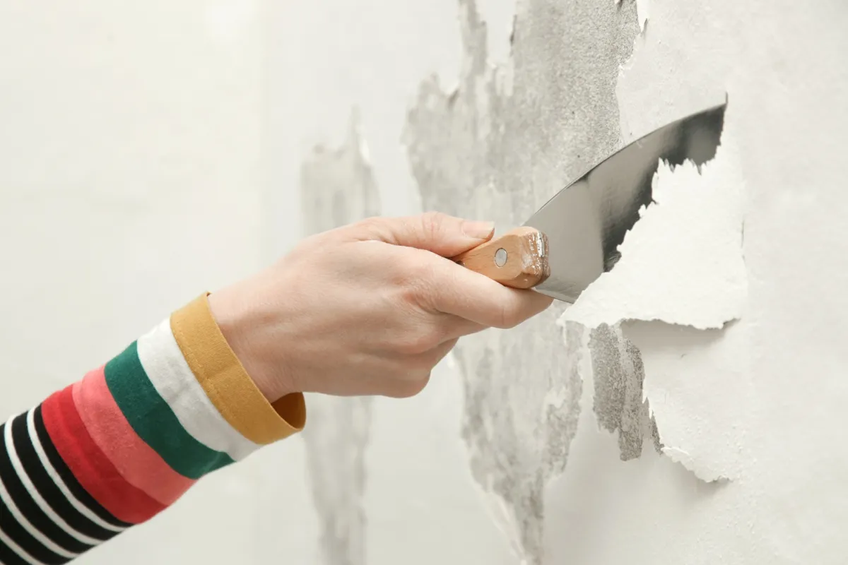 امرأة تزيل الطلاء المتقشر في المنزل