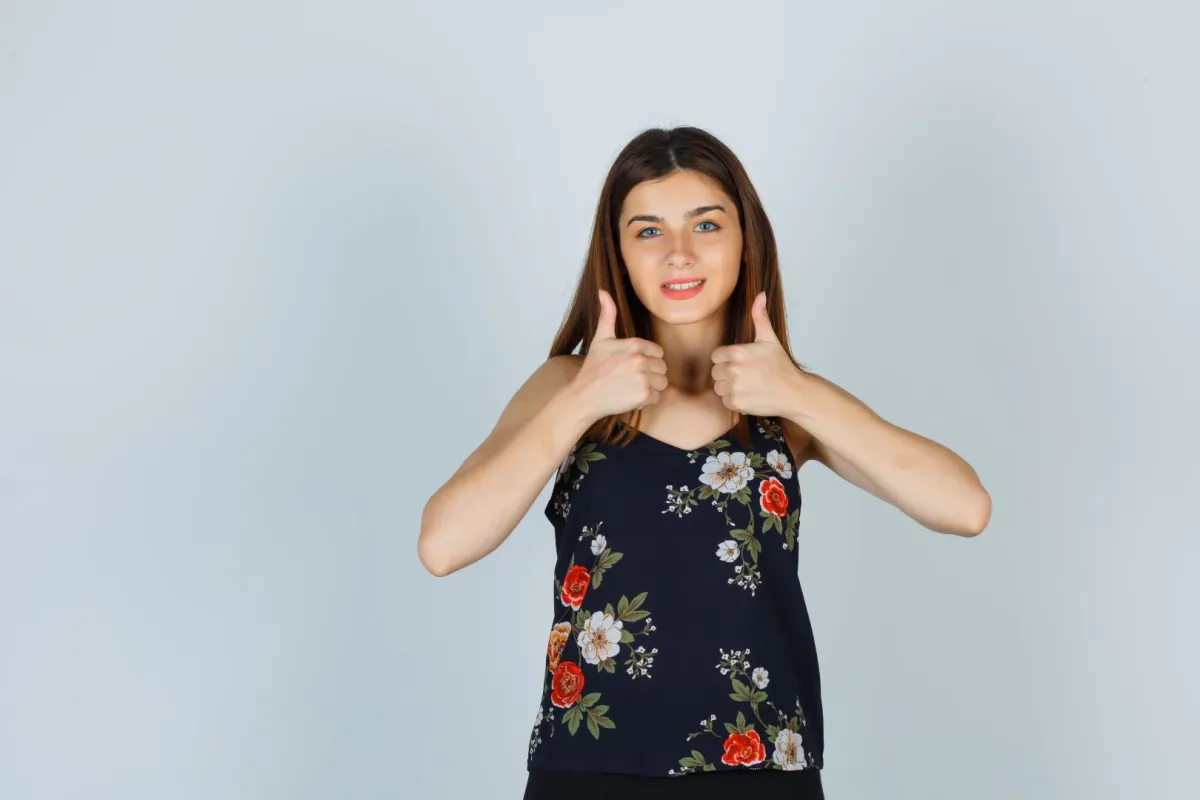 فتاة ترفع إبهامي يديها بسعادة، معبّرةً عن الفرح