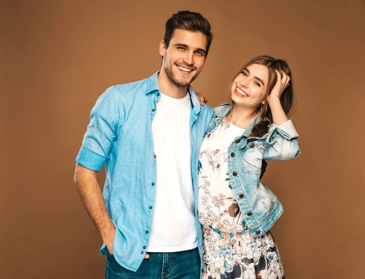 زوجان سعيدان مبتسمان والزوج يضع يده على وسط زوجته بمودة  