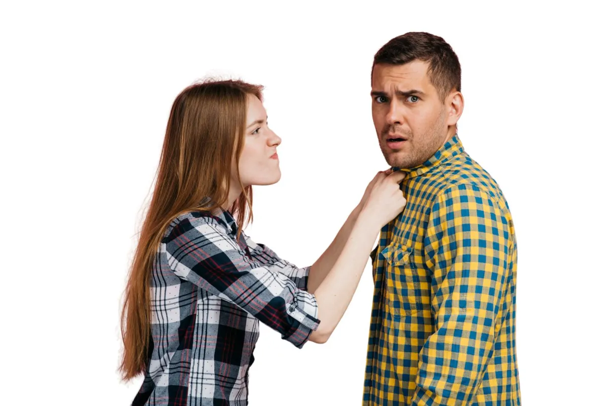 زوجة تعاتب زوجها وتمسكه من طرف قميصه وهو ينظر للأمام باستياء ساخر  