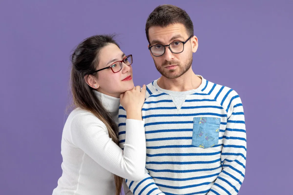 زوجة تضع ذقنها على كتف زوجها وتنظر لعينيه بذكاء  