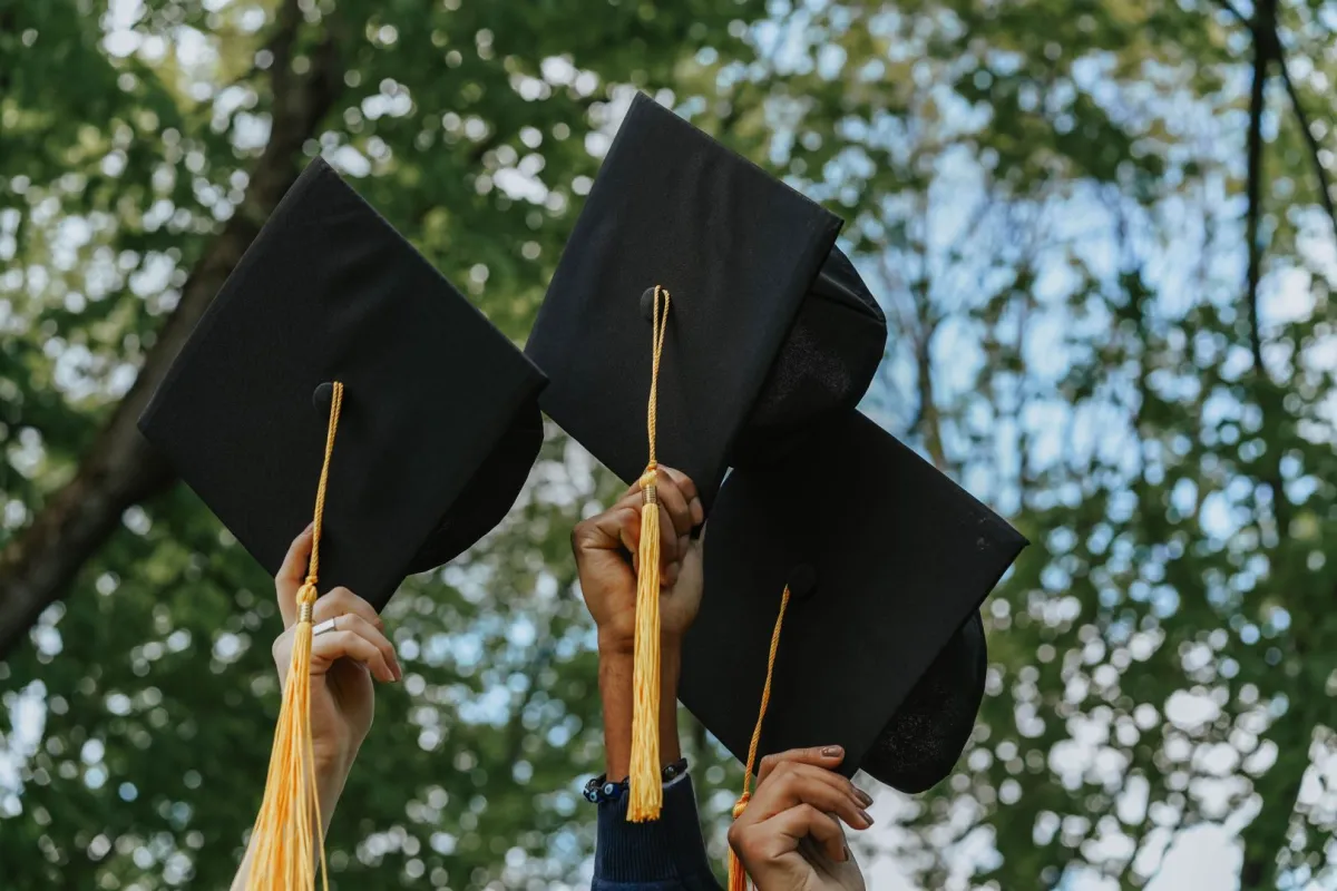مجموعة من الخريجين يرفعون قبعة التخرج لاعلى 