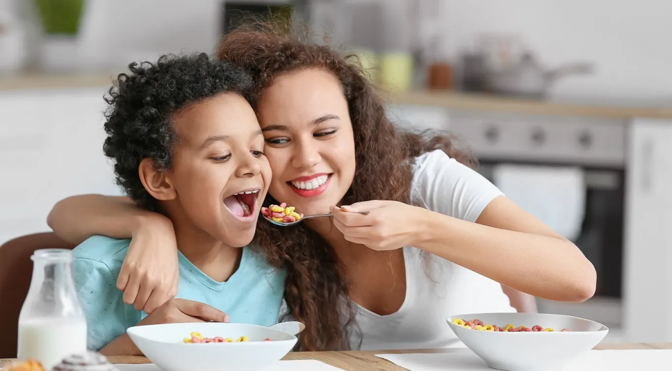 صورة لأم تُطعم طفلها بمرح