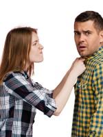 زوجة تعاتب زوجها وتمسكه من طرف قميصه وهو ينظر للأمام باستياء ساخر  