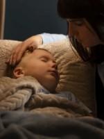 صورة لأم تمسح عرق طفلها النائم