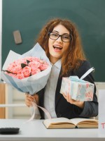 معلمة تحمل باقة من الزهور وهدية أحضرتها لها الأمهات لشكرها   