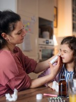 صورة لام تستخدم محلول ملحي لعلاج احتقان أنف طفلتها